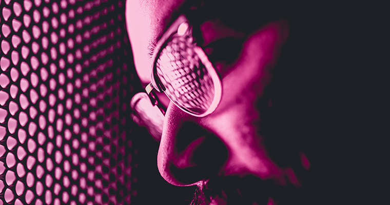 Man som arbetar som kyl- och värmepumptekniker i ett rosa sken.